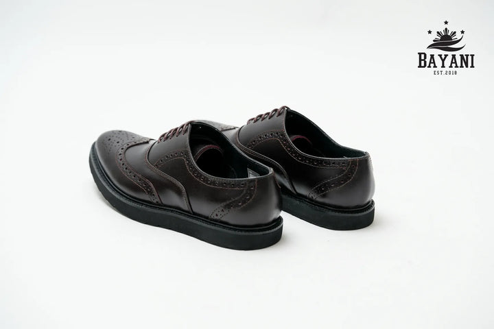 Pair of black leather shoes on a white background with Bayani logo.
