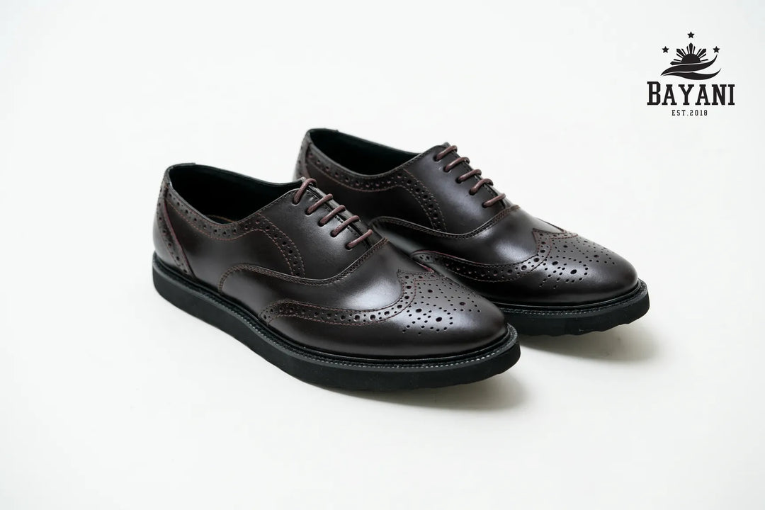 Pair of black dress shoes on a white background with Bayani logo.
