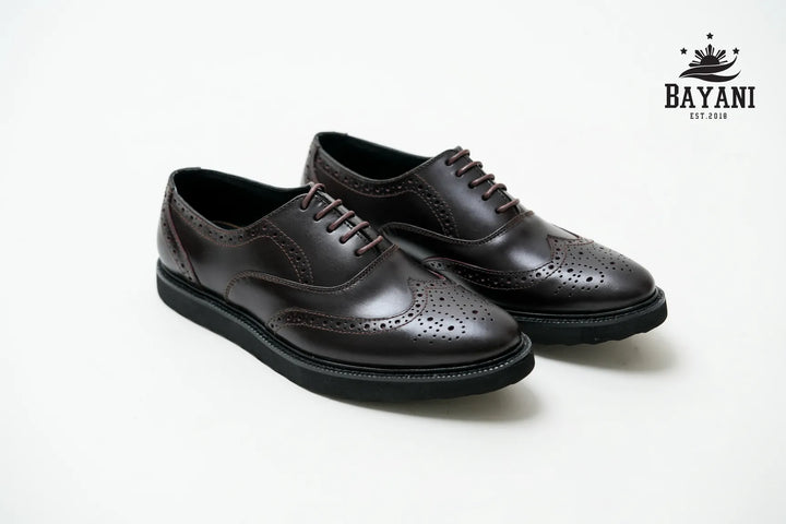 Pair of black dress shoes on a white background with Bayani logo.
