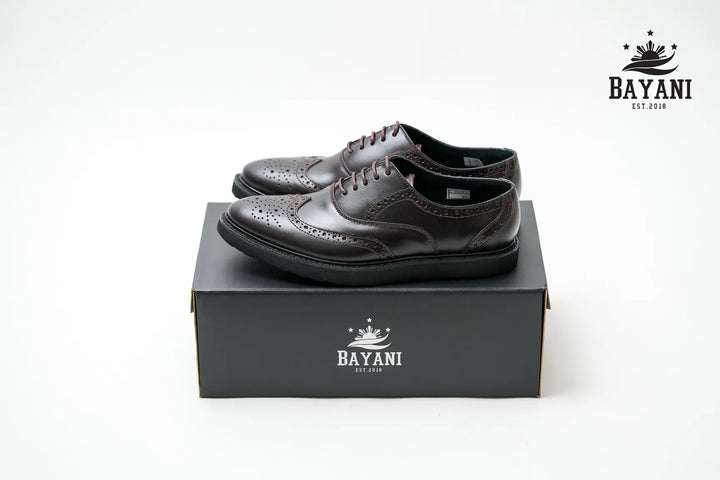 Black leather shoes on a black box with Bayani logo on a white background
