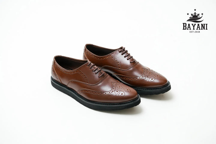 Pair of brown leather shoes with black soles on a white background, featuring the Bayani logo.
