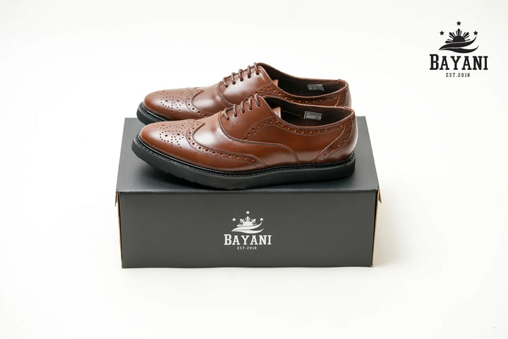Brown leather shoes on a black box with Bayani logo
