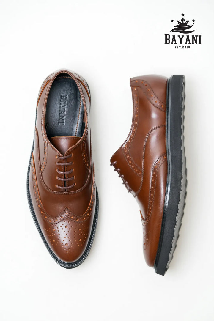 Brown leather shoes with black soles on a white background, featuring the Bayani brand logo.

